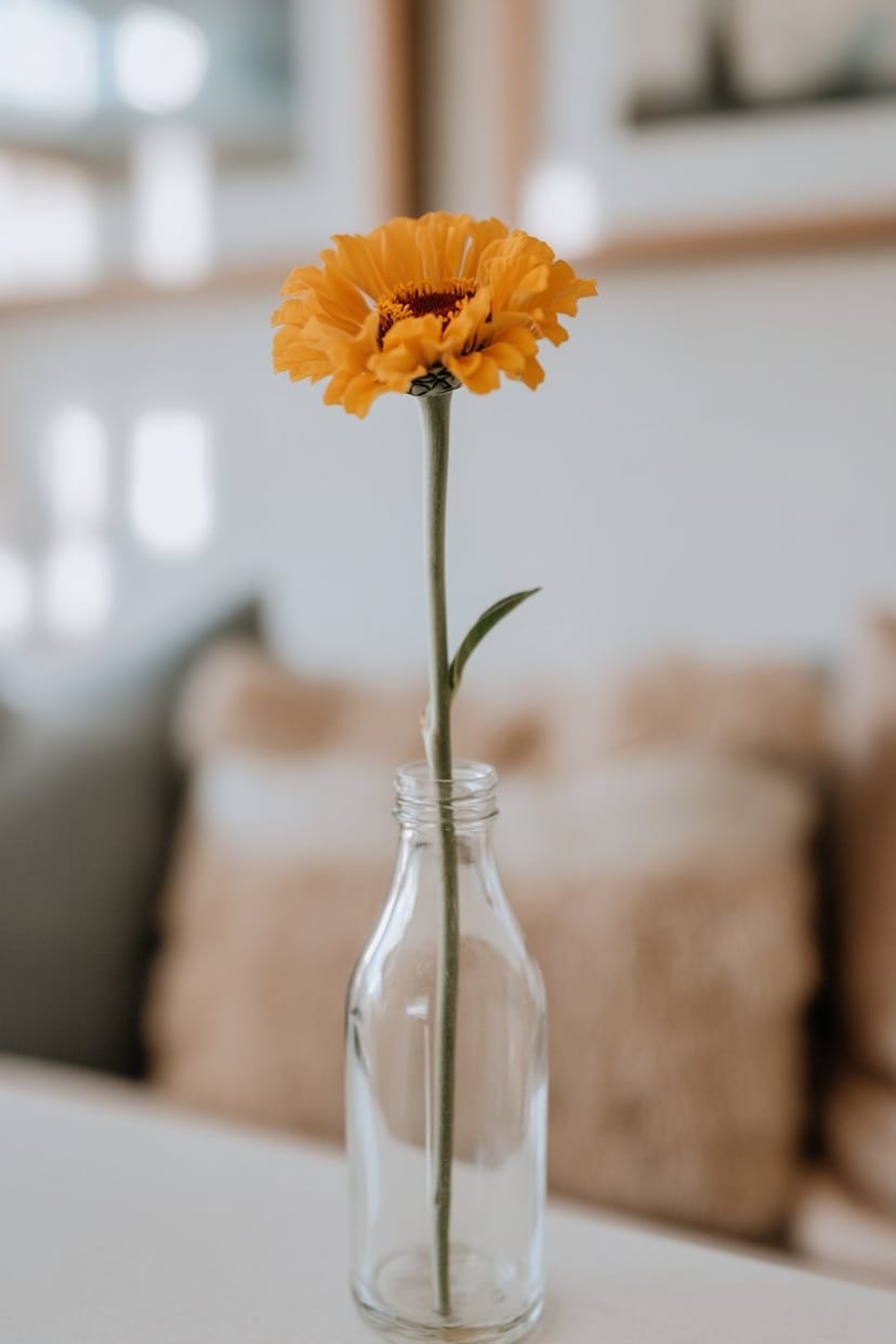 Glasflasche mit Sonnenblume als sommerliche Tischdeko