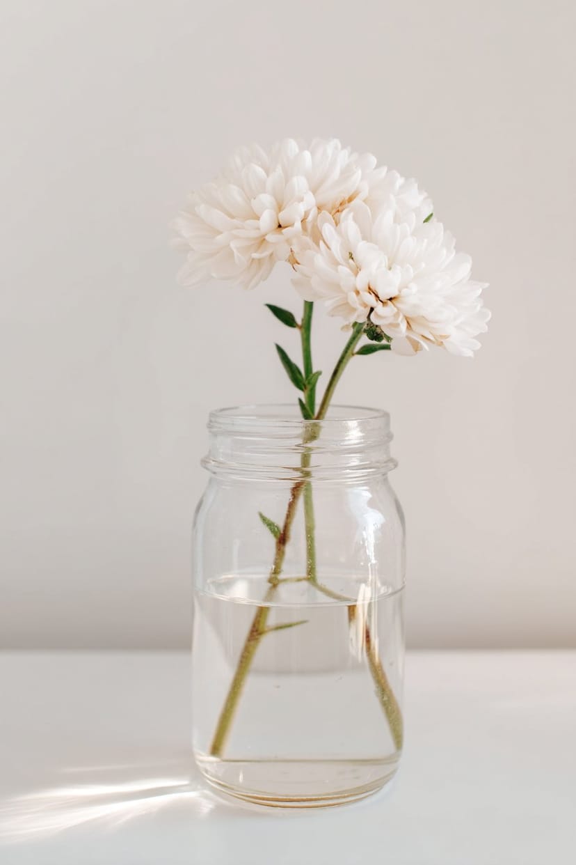 Einmachglas mit Wasser und Blüte als Tischdeko